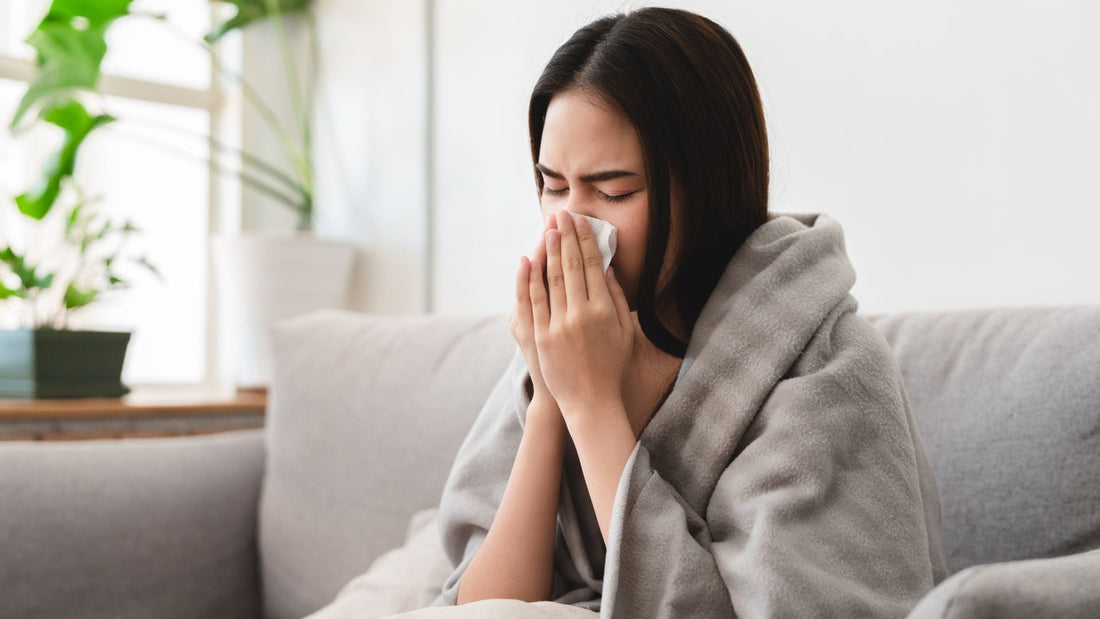 Frau mit Taschentuch auf dem Sofa – Symbolbild für Erkältung im Herbst