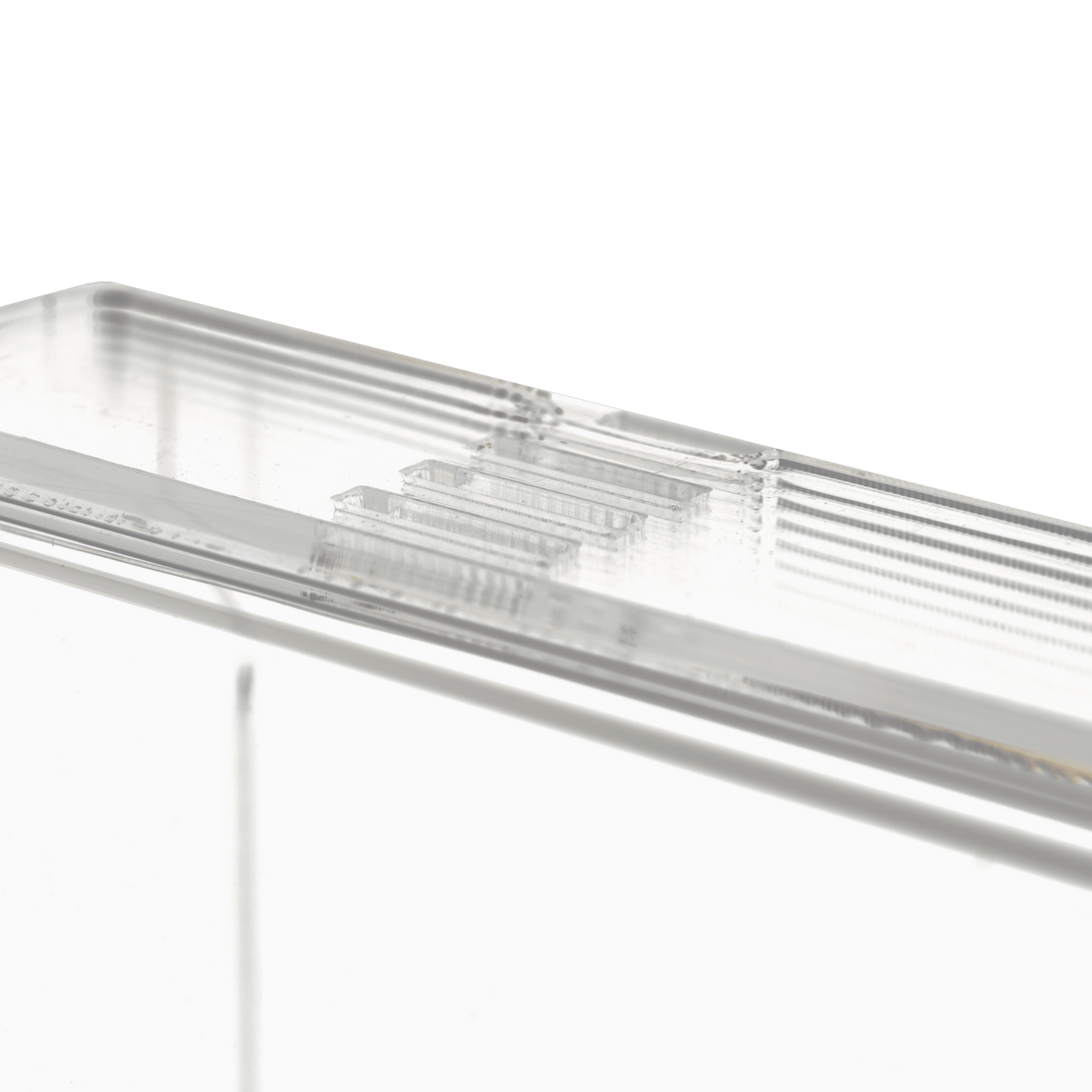 Close-up of the transparent, milky disposable glove dispenser (250 x 135 x 55-90 mm) from AMPri Handelsgesellschaft mbH, a rectangular acrylic dispenser holder with ribbed edges on a plain white background.