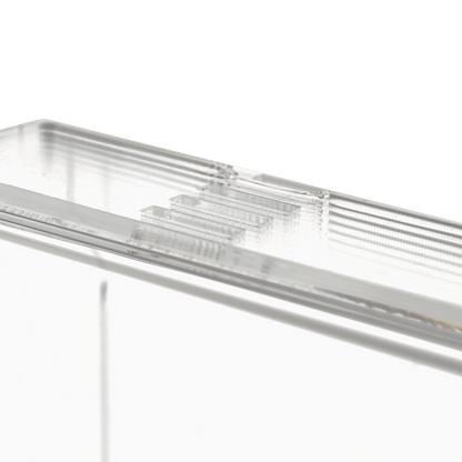 Close-up of the transparent, milky disposable glove dispenser (250 x 135 x 55-90 mm) from AMPri Handelsgesellschaft mbH, a rectangular acrylic dispenser holder with ribbed edges on a plain white background.