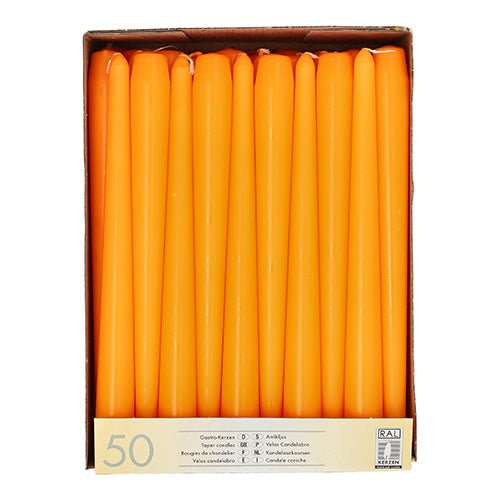 A box with 50 Starpak taper candles (Ø 2.2 cm, 25 cm), arranged upright in rows and viewed from above. The neatly packed orange candles have a label with product information on the bottom of the box.