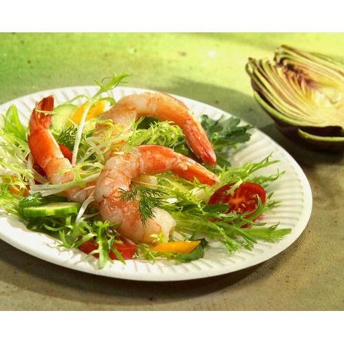 A PAPSTAR 100 plates, cardboard "pure" round from PAPSTAR GmbH holds shrimp on mixed greens, sliced cucumbers, yellow peppers, and cherry tomatoes. In the background rests a halved radicchio on a green surface.