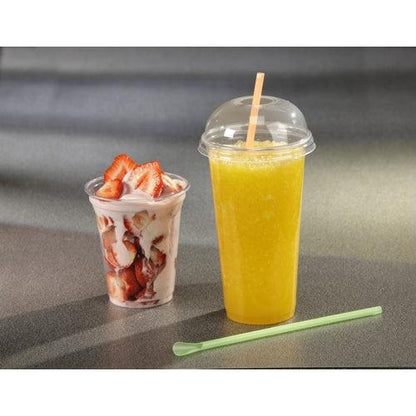 A Starpak 50 drinking cup "Hurricane" PET crystal-clear filled with strawberries and yogurt stands next to a tall To-Go cup with orange slush, which is equipped with a dome lid and straw. On the gray countertop next to it lies a green stirrer.