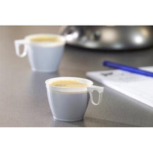 Two white Starpak 60 coffee cups (0.18 l, PS, Ø 7.8 cm, 6 cm)—one in focus and one out of focus in the background—are sitting on a gray surface; a pen and a piece of paper are partially visible on the right side.