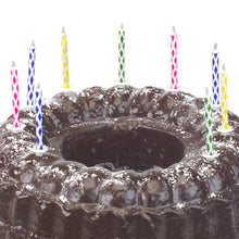 A chocolate cake sprinkled with powdered sugar is decorated with colorful PAPSTAR magic candles 6 cm (10 pieces per pack, with holder, from PAPSTAR GmbH) against a plain white background.