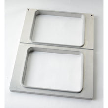 The Duni GmbH cassette DF15/25 for CPET trays 960-1500 ml - 2-use is a rectangular metal frame with two vertically arranged openings, brushed finish and rounded edges - perfect for storing CPET trays on any white surface.