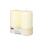 Two Starpak pillar candles Ø 80 mm with flat top stand in a simple cardboard holder with a label – a touch of timeless elegance for any ambiance.