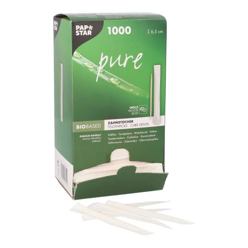 A green box from PAPSTAR GmbH with the label "Toothpick pure" (1000 pieces, round, wood, 6.5 cm) is partially open, revealing environmentally friendly toothpicks, in front of which several hygienically packaged pieces lie.