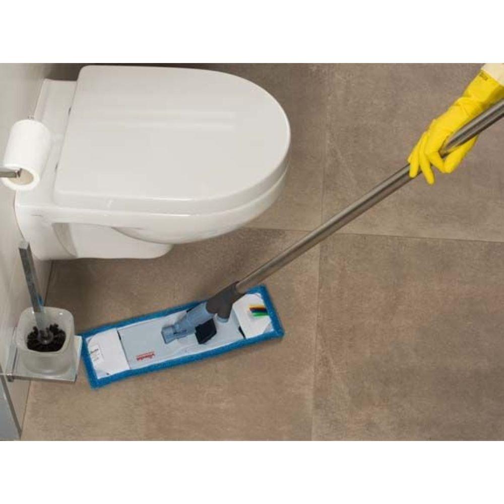 A person with yellow gloves efficiently wipes the tiled bathroom floor next to a white toilet with the Vileda Professional SprayPro stainless steel mop holder from Vileda GmbH, equipped with a pad bordered in blue. Nearby is a holder where the toilet brush is stored.