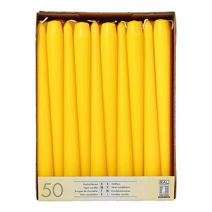 A cardboard box from Starpak contains 50 white taper candles (Ø 2.2 cm - 25 cm), arranged upright in rows. The label on the front contains product information in multiple languages, including "paraffin candles."