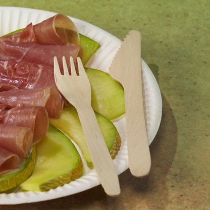 Enjoy snacks on a green surface with apple slices and sausage, paired with PAPSTAR GmbH wooden forks "pure" 16.5 cm - eco-friendly, sturdy, and sustainable. Each folding box contains 100 pieces of sustainable disposable cutlery.