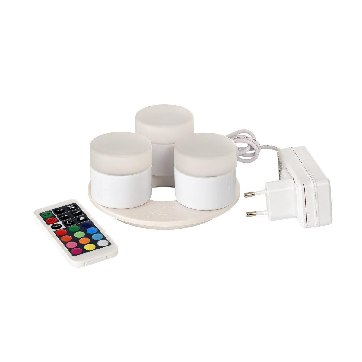 The Duni GmbH Mini Multicolour LED Set includes three small, round LEDs with a charging station, a white power adapter, and a remote control for different colors and functions - perfect for creative lighting.