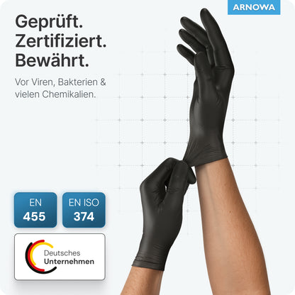 A person is wearing ARNOMED LATEX BLACK powder-free disposable gloves made of black latex from ARNOWA GmbH, certified according to EN 455 and EN ISO 374 against viruses, bacteria, and chemicals; logo and "ARNOWA" brand are visible.
