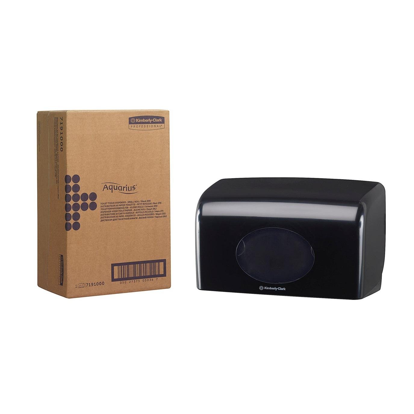 A cardboard box labeled "Aquarius" stands next to a black Kimberly-Clark GmbH Aquarius™ toilet paper dispenser (small rolls, 18.00 x 29.80 x 12.80 cm) with a transparent oval window, both on a solid white background.