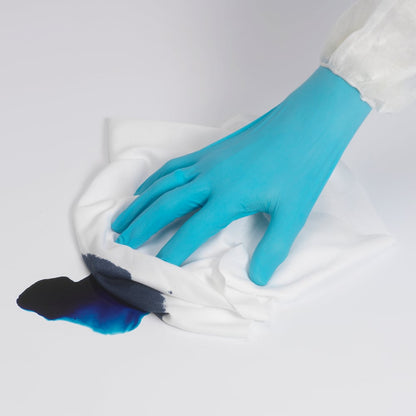 A person wearing a blue glove wipes a dark blue liquid on a white surface with a Kimtech® Polyester flat cloth (White, Large, 8x50 sheets) from Kimberly-Clark GmbH.