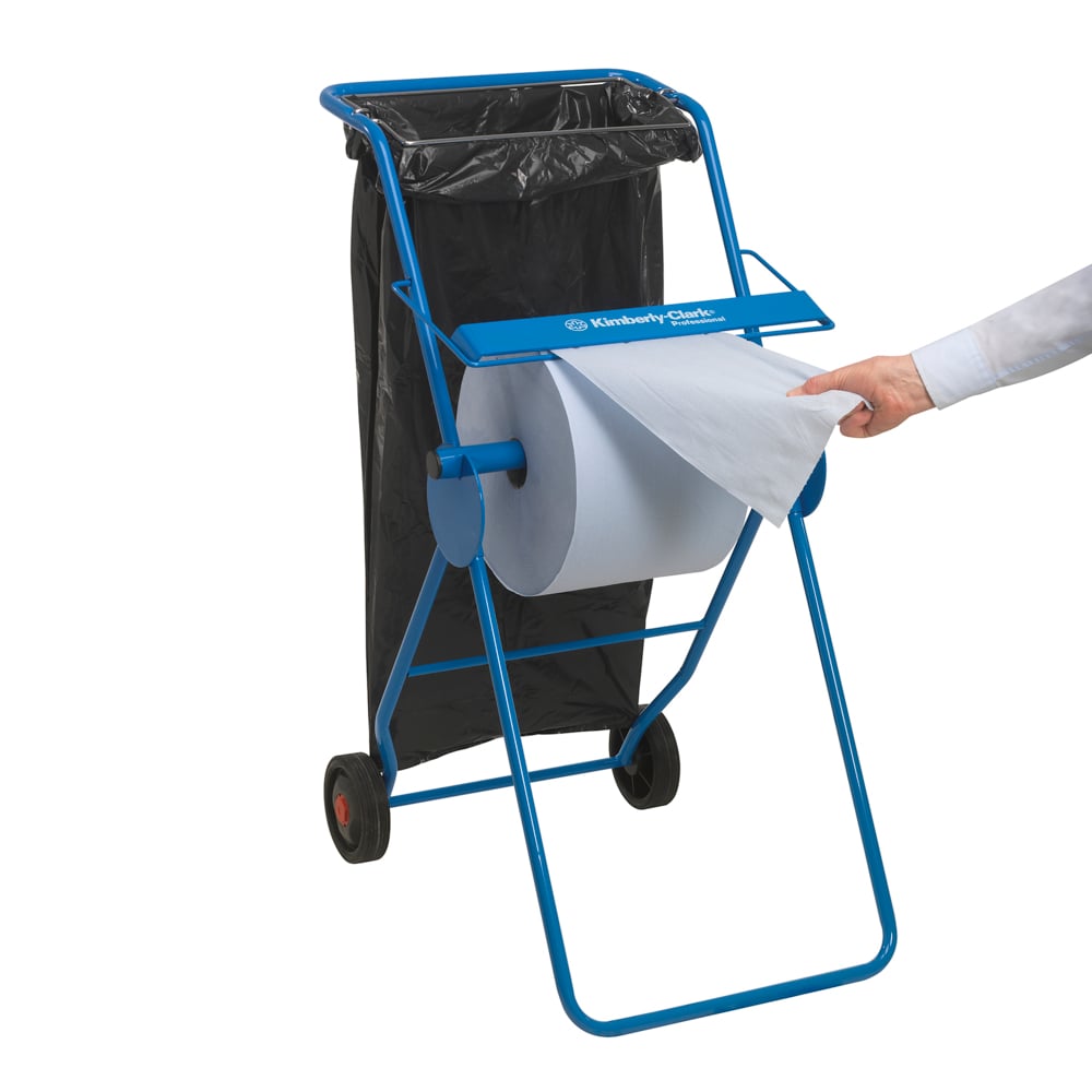 The blue metal floor stand dispenser from Kimberly-Clark GmbH holds a large roll of WypAll® L30 paper wiper (750 sheets) for industrial cleaning. It features two wheels and a black waste bag on the back with easy sheet dispensing.