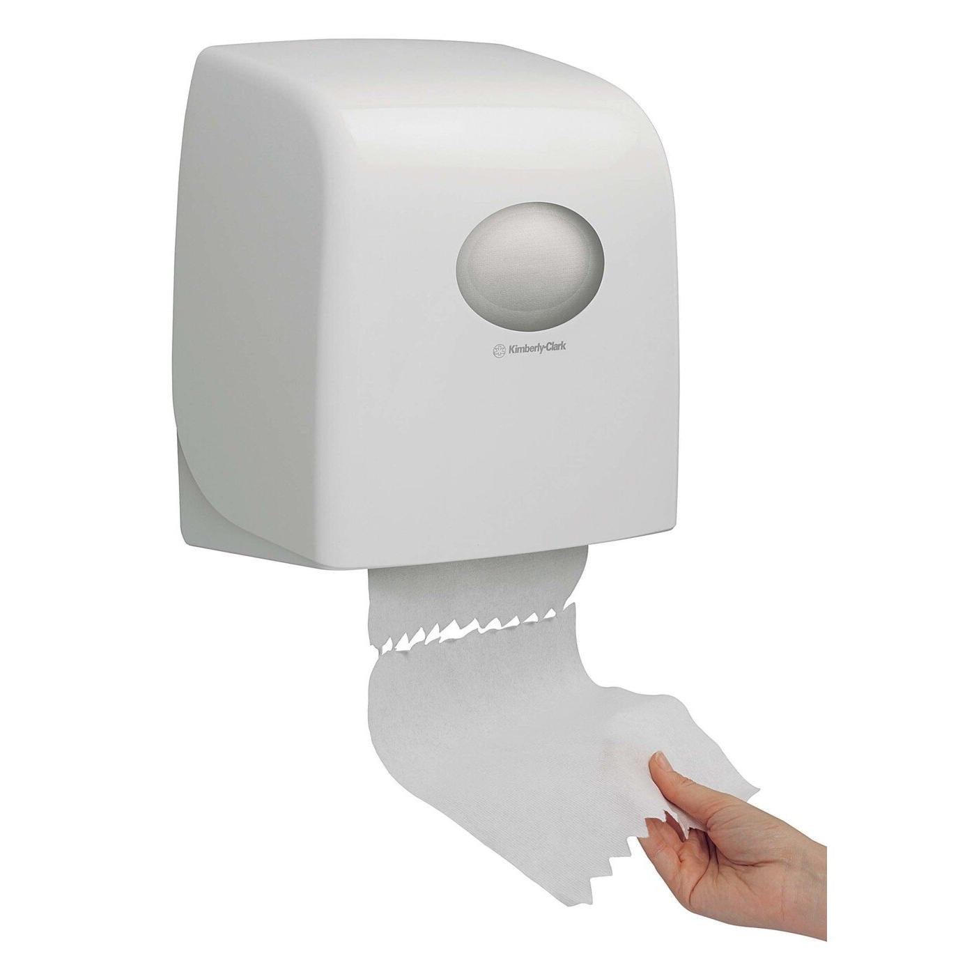 A hand dispenses paper towels from a white, wall-mounted Aquarius™ Slimroll™ roll towel dispenser from Kimberly-Clark GmbH, which has a visible roll inside.