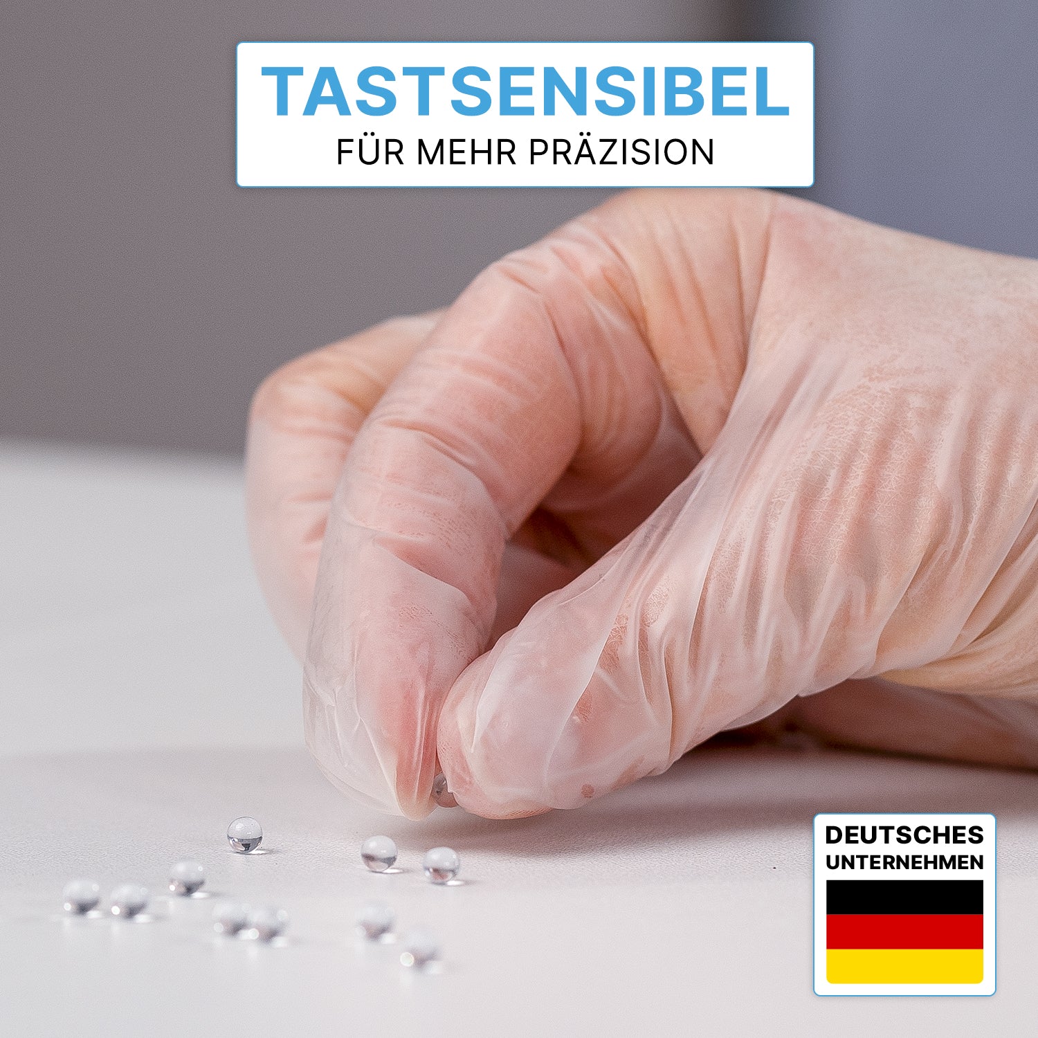 A hand in ARNOMED VINYL PF tactile-sensitive disposable gloves from ARNOWA GmbH grabs a silver ball from several on a white surface. At the top it says: "Tactile-sensitive for more precision." A German flag can be seen at the bottom right.