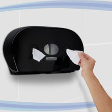 A person pulls toilet paper from a black Kimberly-Clark Professional™ toilet tissue dispenser - center-pull (Jumbo) by Kimberly-Clark GmbH, which is mounted on a tiled wall with blue curved stripes.