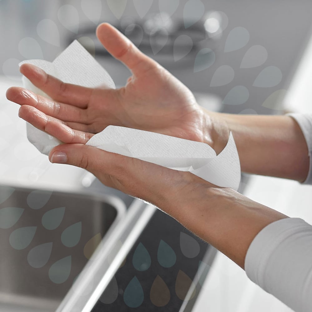 A person is drying their hands over a sink using Kleenex® Folded Hand Towels—White/Large (15 clips x 124 sheets | carton) by Kimberly-Clark GmbH, with both hands and part of the sink visible in the background.