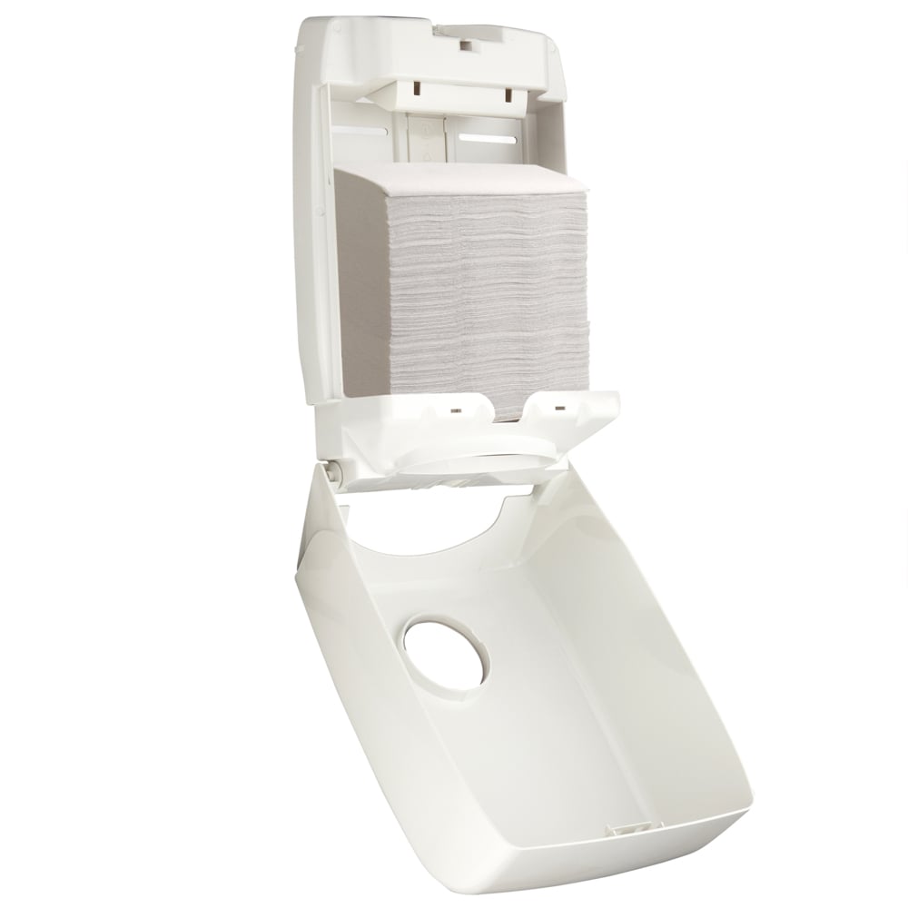 A wall-mounted Aquarius™ dispenser for folded towels (Interfold, White) from Kimberly-Clark GmbH is open, showing folded paper towels inside. The foldable front cover reveals the interior and the slot for hygienic towel removal.