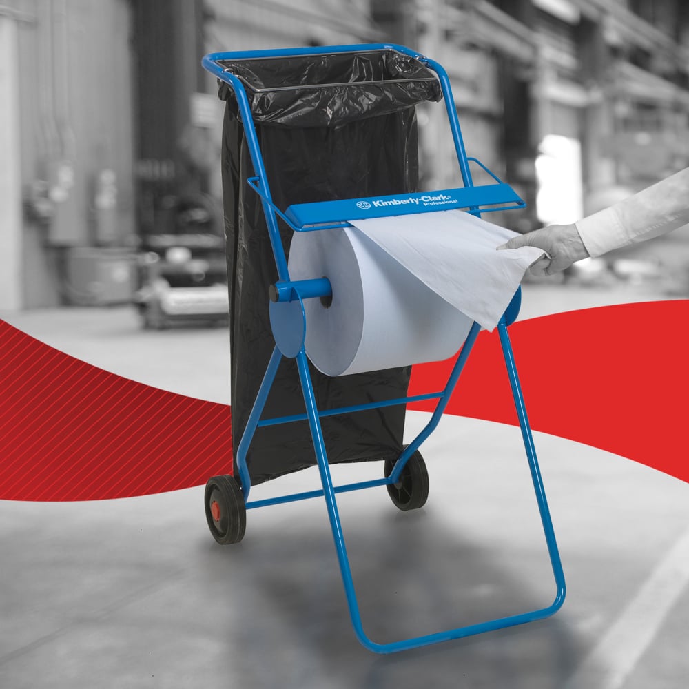 A person uses a WypAll® L30 paper wipe from Kimberly-Clark GmbH from the extra-wide large roll on a blue dispenser with a trash bag in an industrial setting - perfect for industrial cleaning tasks.
