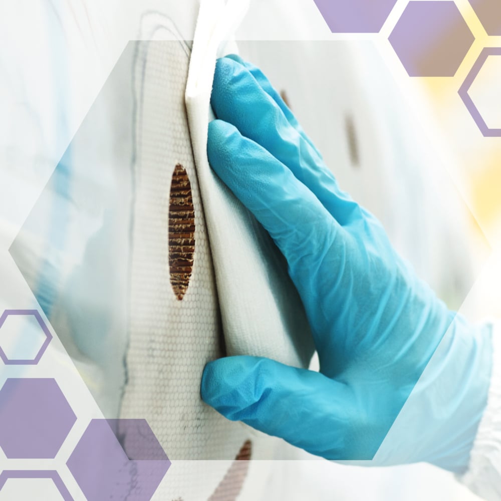 A gloved hand cleans a circular brown stain on a white surface with Kimtech® Science Precision Wipes from Kimberly-Clark GmbH. Semi-transparent hexagons are overlaid on the image.