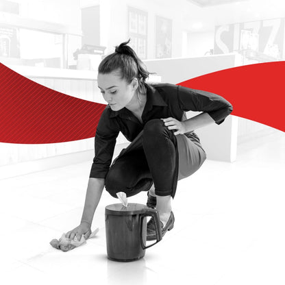A woman in dark clothing cleans a tiled floor with a WypAll® Reach™ paper towel for food & hygiene - centerfeed from Kimberly-Clark GmbH. A cleaning bucket is nearby; the black-and-white background is accented with a bold red wave that highlights hygiene.