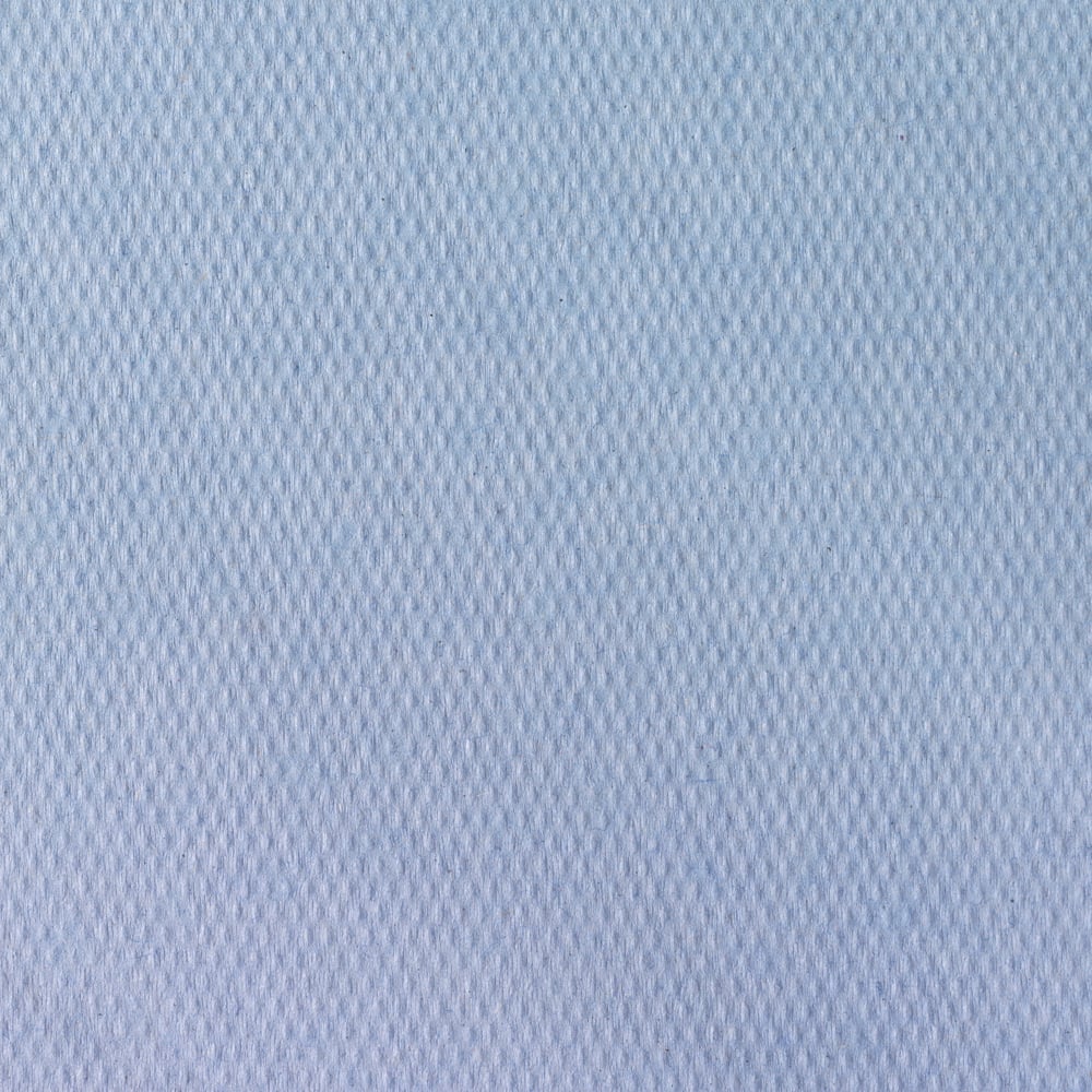 Close-up of Scott® doctor's rolls from Kimberly-Clark GmbH (38.00 cm x 51.00 cm), a light blue, textured fabric with a subtle diamond pattern, commonly used for examination couches in medical facilities. The smooth surface fills the frame.