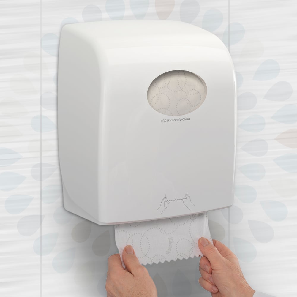 A person pulls a Kleenex® ULTRA™ hand towel roll (White, 150m) from Kimberly-Clark GmbH from a wall dispenser in a toilet, ensuring hygienic hand drying. Packaging: 6 rolls/box.