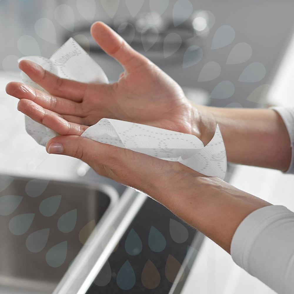 A person wipes their left hand with a white Kleenex® Ultra™ roll towel (2-ply, E-roll Large) from Kimberly-Clark GmbH over a sink for hygienic drying. Water drop graphics overlay the image.