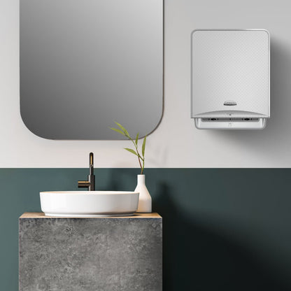 A modern bathroom with a round white sink on a concrete countertop, a black faucet, a green plant, a rectangular mirror, and a wall-mounted Kimberly-Clark GmbH Kleenex® Ultra™ E-roll Slimroll™ 2-ply white paper towel dispenser.