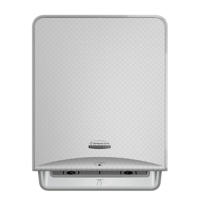 A silver mosaic, wall-mounted Kimberly-Clark Professional™ Icon™ electronic No Touch-Loose Module Roll from Kimberly-Clark GmbH with a patterned front panel, central logo, and a slot at the bottom for touchless towel dispensing.