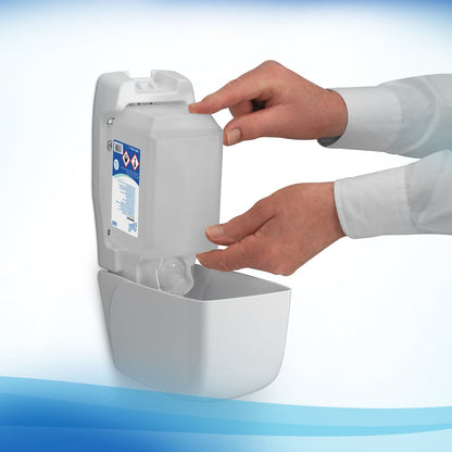 A person fills a wall-mounted dispenser with a Scott® CONTROL alcohol-based hand sanitizer foam 1L cartridge from Kimberly-Clark GmbH and shows the warning sign. Their hands are visible and they are wearing a white long-sleeved shirt.