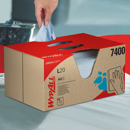 A hand pulls a WypAll® L20 General Clean wipe from a blue BRAG™ Box by Kimberly-Clark GmbH, which contains 280 sheets, and places it on a smooth surface.