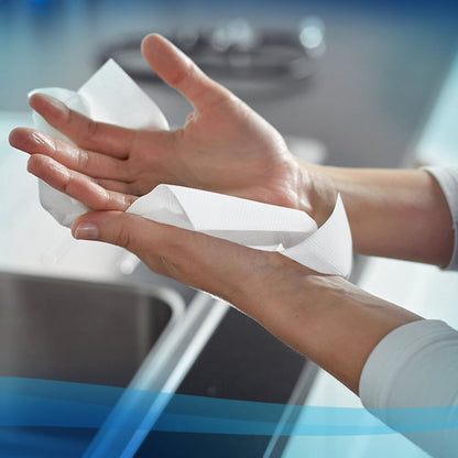 A person uses Scott® EXCELLENT Hand Towels - Interfold/White/Small from Kimberly-Clark GmbH for hygienic hand drying in a kitchen, with a sink and countertop in the background; each box contains 20 packs with 190 sheets.