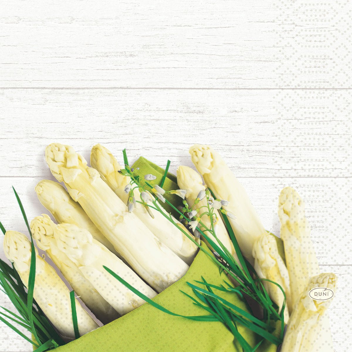 A 50-pack of Duni GmbH napkins 33 cm, 3-ply, 1/4-fold features a white asparagus motif with green accents and white blossoms on a white wooden background - perfect for the spring table.