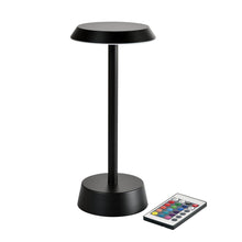 The NOUR Wireless LED Lamp in Graphite by Duni GmbH, with a modern design and round base, is shown alongside a remote control with colorful buttons - perfect for your living room decor.
