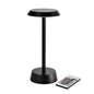 The NOUR Wireless LED Lamp in Graphite by Duni GmbH, with a modern design and round base, is shown alongside a remote control with colorful buttons - perfect for your living room decor.