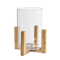 The decorative table lantern ESME by Duni GmbH consists of a cylinder made of clear glass (15x15 cm) on a wooden stand with four legs and a cross-shaped base. It combines modern style with functional design, similar to the minimalist Esme Box.