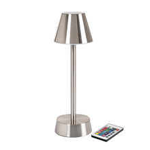 The LED lamp wireless ZELDA silver by Duni GmbH with a conical shade and cylindrical base stands on a white background. Next to it is a remote control for energy-saving, modern lighting solutions (1 piece).