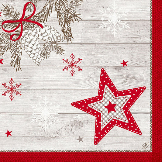A rustic wooden background with white pine cones, red ribbon, snowflakes, and a red gingham star, bordered by red textured fabric with a quilted edge - ideal for highlighting the Dunilin napkins 40x40cm from Duni GmbH.
