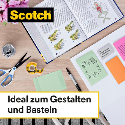 A desk with creative tools - scissors, can, pen, colored paper, sticky notes, and an open biology book - is equipped with Scotch® double-sided tape (2 rolls, 12 mm x 6.3 m) from 3M Deutschland GmbH. Ideal for designing and crafting.