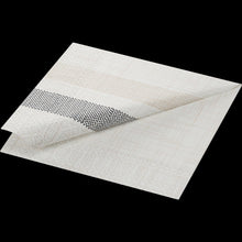 The white square dispenser napkin 33x33 Rigato black napkin from Duni GmbH is folded at one corner and features a textured, horizontal pattern in beige, gray, and black - ideal for stylish presentation in the catering industry. Package: 300 pieces.
