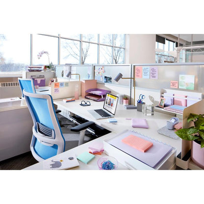 A modern office with white desks, blue chairs, a laptop, plants, and the Post-it® Super Sticky Z-Notes Boost Collection from 3M Deutschland GmbH (76x76 mm, 90 sheets per pad, 100% PEFC). Large windows provide natural light and views of trees.