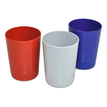 Three Nölle Profi Brush toothbrush cups made of plastic, assorted colors (by Nölle Profi Brush Bürsten- & Pinseltechnik e.K.), stand side by side in the bathroom: one red, one light gray speckled, and one blue. All are handleless and cylindrical.