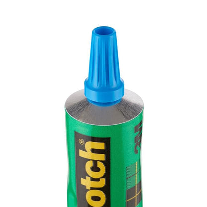 Close-up of an upright green 30 ml tube labeled "Scotch® transparent solvent-free adhesive for household use" from 3M Deutschland GmbH, with a black and yellow logo and blue plastic cap.