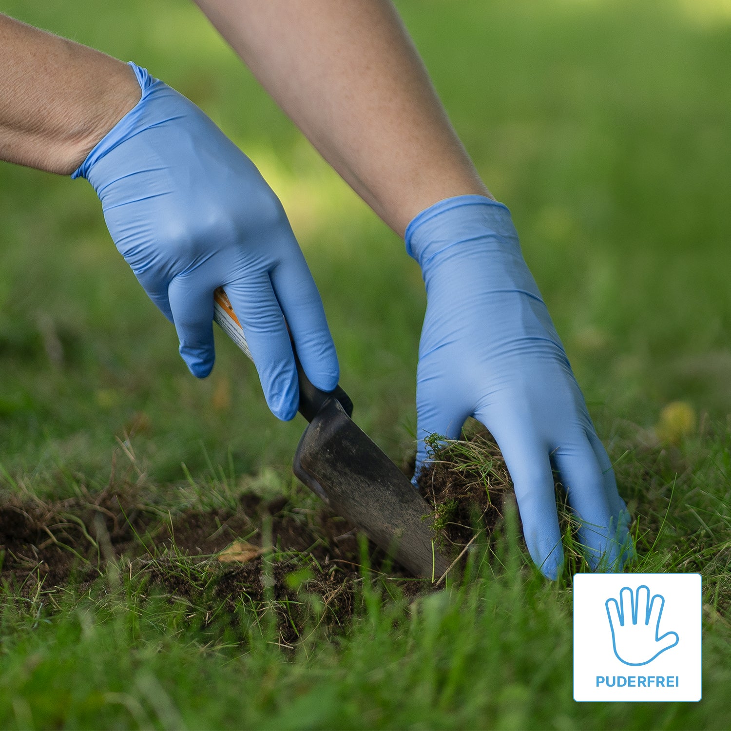 A person wearing ARNOMED NITRIL BLUE XTRA STRONG extra thick nitrile disposable gloves from ARNOWA GmbH uses a hand trowel to dig up soil on a lawn. In the corner, there is a "powder-free" label with a glove symbol.