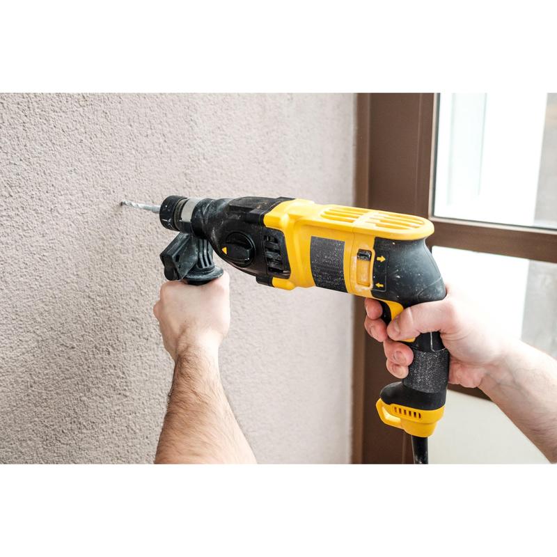 A person is drilling into a beige wall next to a glass door - an ideal project for the Scotch® Extremium™ Ultra High Performance Tape DT17 (25 m x 48 mm, 1 roll/package) from 3M Deutschland GmbH.