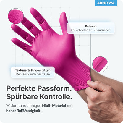 A person puts on a pink ARNOMED NITRIL MAGNOLIA disposable glove from ARNOWA GmbH with their left hand. The glove has textured fingertips, a rolled edge, and is tear-resistant. The ARNOWA logo is visible in the upper right corner.