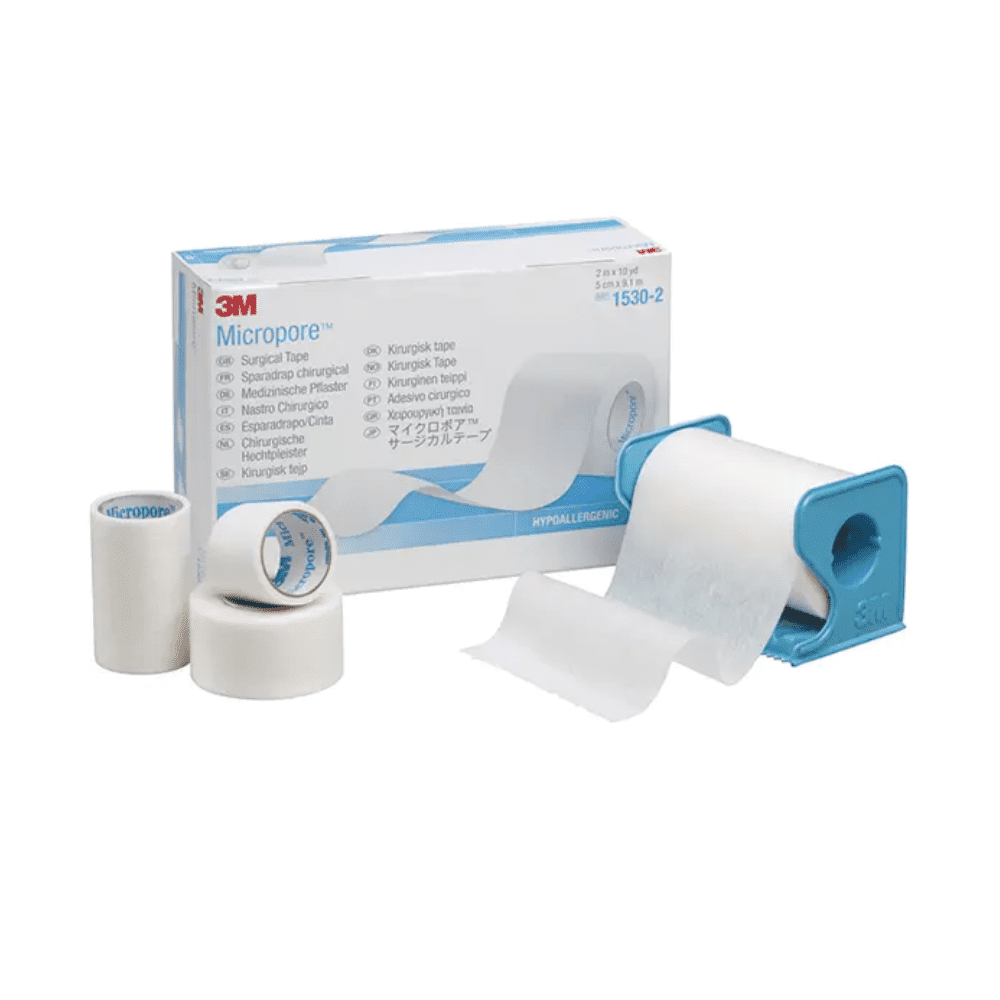 The image shows a 3M Healthcare Germany GmbH 3M-Medica Micropore tape, skin-colored – 12 pieces | Pack (12 pieces)-box with tapes in various sizes in front. A tape roll is in a blue dispenser, while two more tape rolls and a smaller roll stand upright next to the box. The hypoallergenic tape is white.